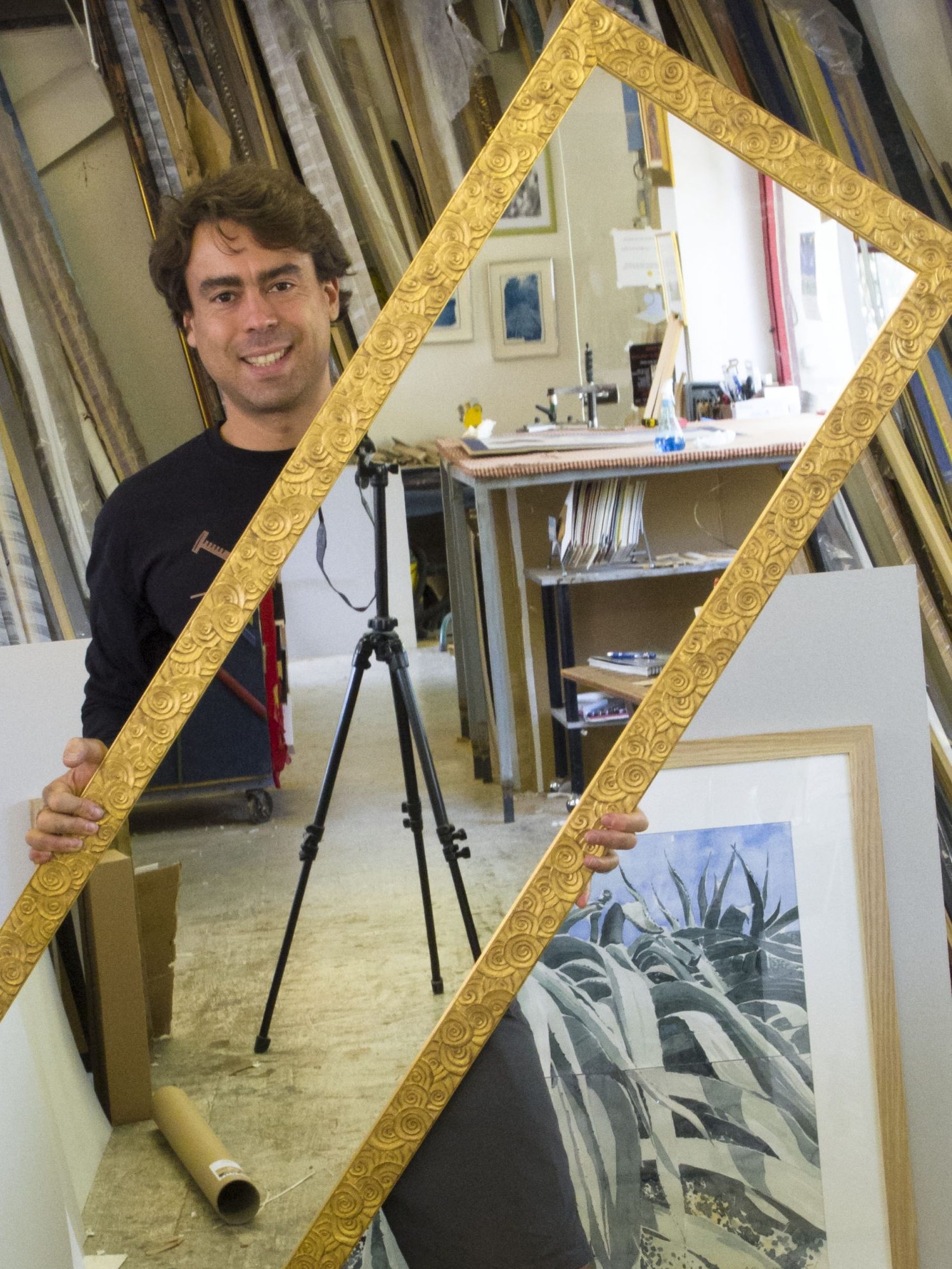 encadrement-dun-grand-cadre-dore Julien Silvestro porte un grand cadre doré en cours de montage dans son atelier d'encadrement